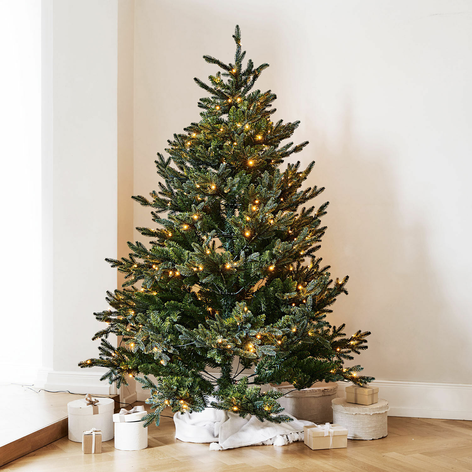 Sapin de Noël Franck Sapin artificiel vert avec lumières LED chaudes posé sur un sol en bois avec des cadeaux autour