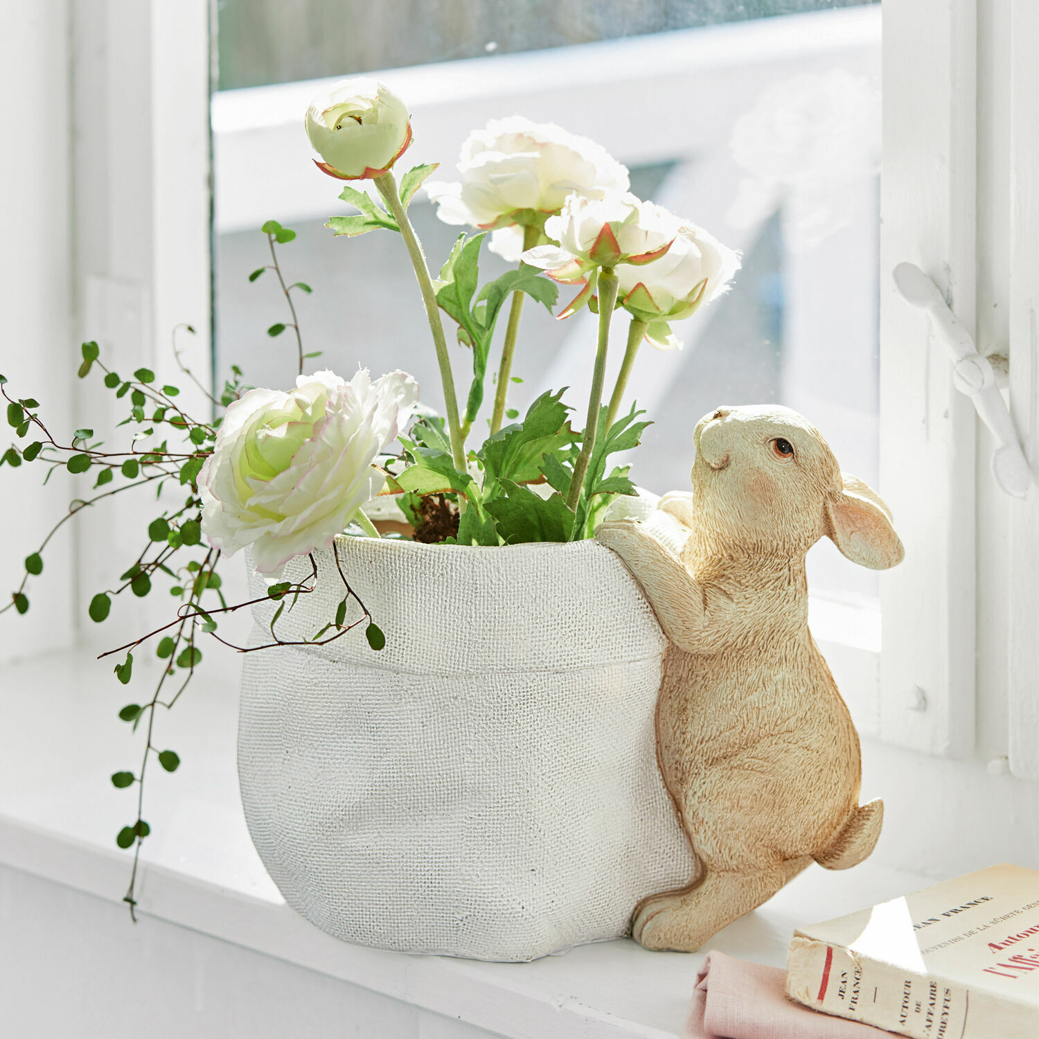 Cache-pot Irianna Cache-pot en tissu blanc avec décoration lapin et fleurs blanches artificielles sur rebord de fenêtre
