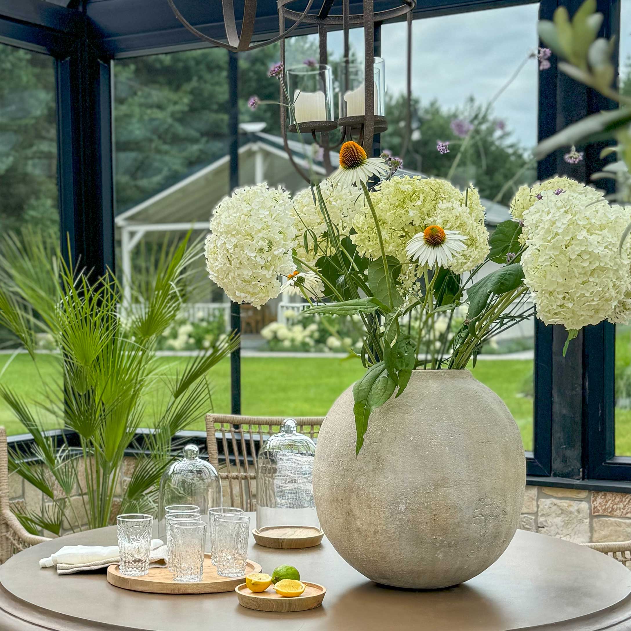 Grand vase rond en béton avec fleurs blanches sur table dans jardin, décoration intérieure et extérieure