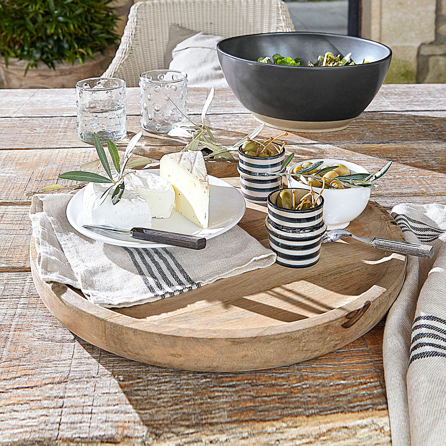Plateau Helier Plateau en bois avec fromages, olives et tasses en céramique sur une table rustique en bois clair