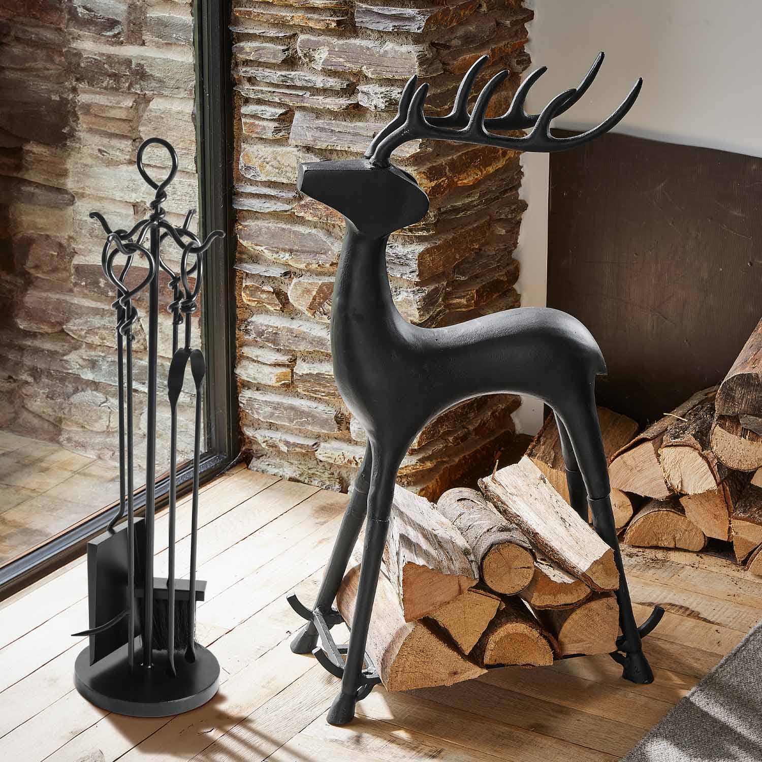 Support à bûches en métal noir en forme de cerf avec outils de cheminée et bûches en bois à côté