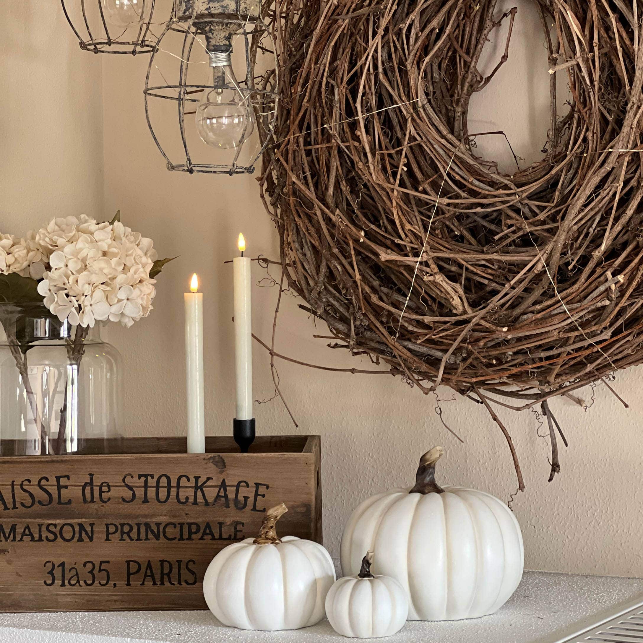 Décoration intérieure avec citrouilles blanches, caisse en bois et couronne naturelle en branches