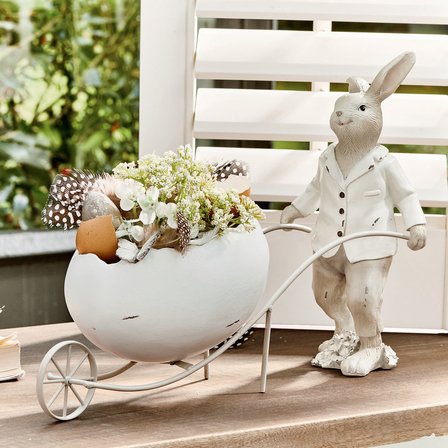 Lapin Jaris Lapin décoratif blanc avec œuf en céramique et fleurs dans un chariot en métal sur table.