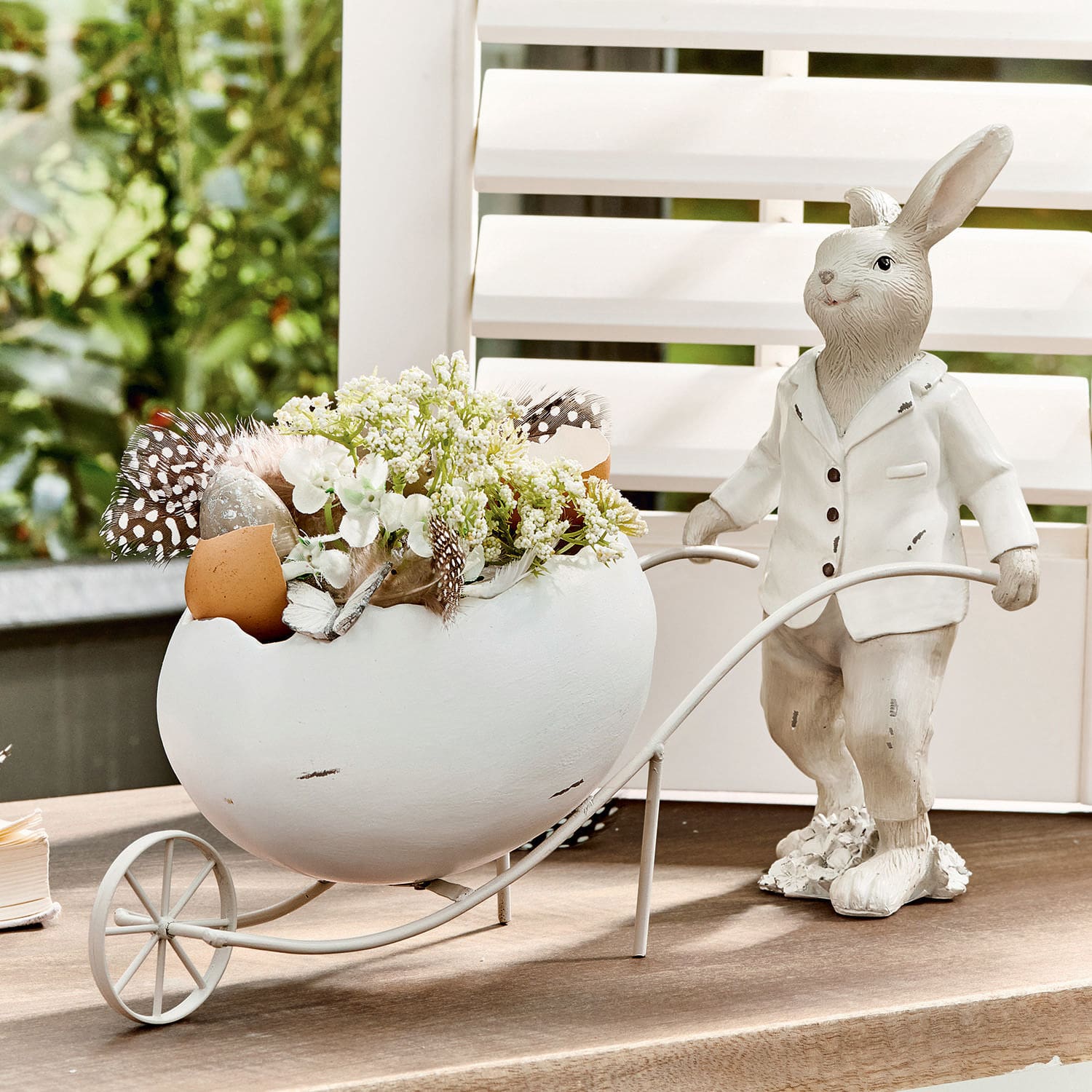 Lapin Jaris Lapin décoratif blanc avec œuf en céramique et fleurs dans un chariot en métal sur table.