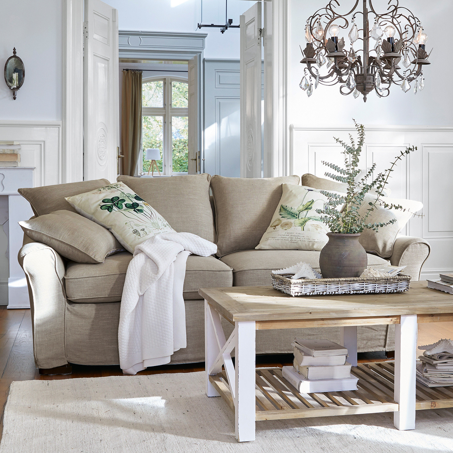 Canapé Long Beach Canapé beige en tissu avec coussins décoratifs et table basse en bois dans un salon lumineux