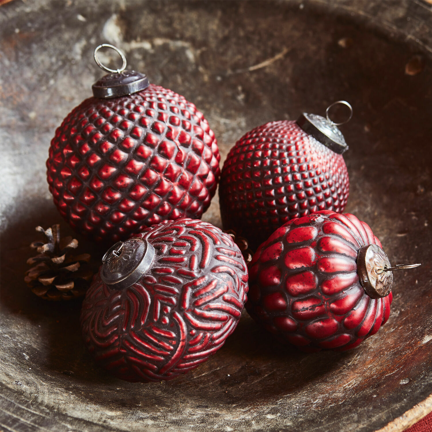 Lot de 4 boules de Noël Meyen Quatre boules de Noël rouges texturées posées dans un bol en bois, décoration festive traditionnelle