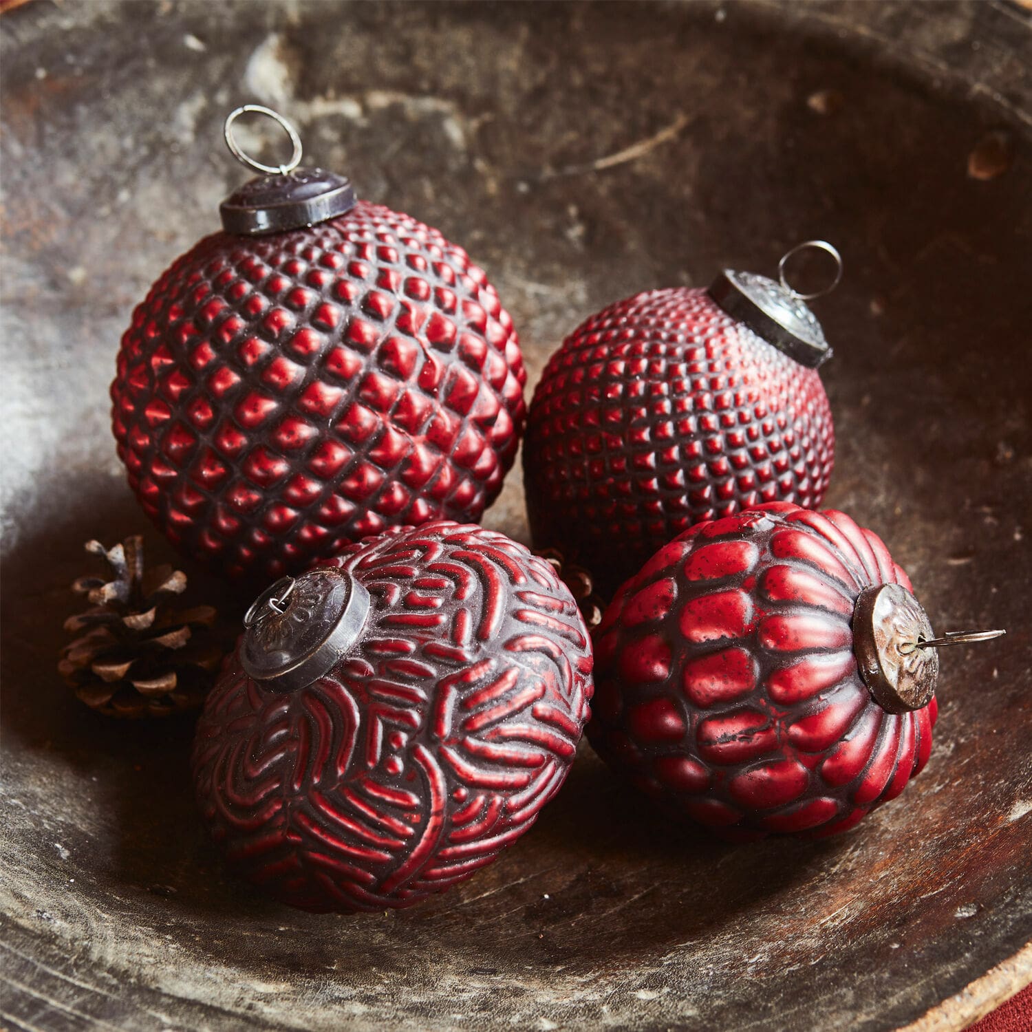 Lot de 4 boules de Noël Meyen Quatre boules de Noël rouges texturées posées dans un bol en bois, décoration festive traditionnelle