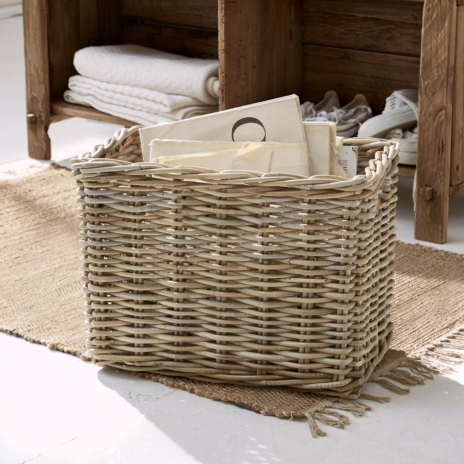 Panier en osier naturel avec documents, posé sur un tapis dans un intérieur lumineux, rangement décoratif