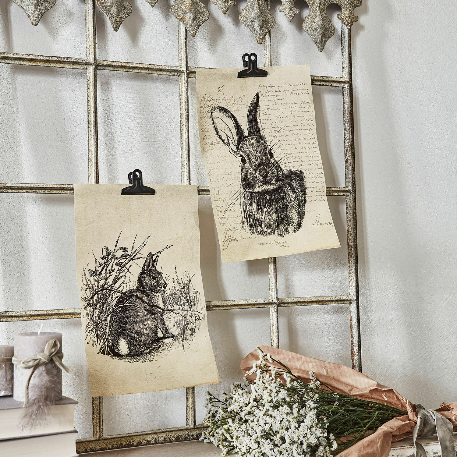 Lot de 2 tableaux Meursault Deux dessins de lapins sur papier fixés à une grille métallique avec fleurs blanches et bougies à côté