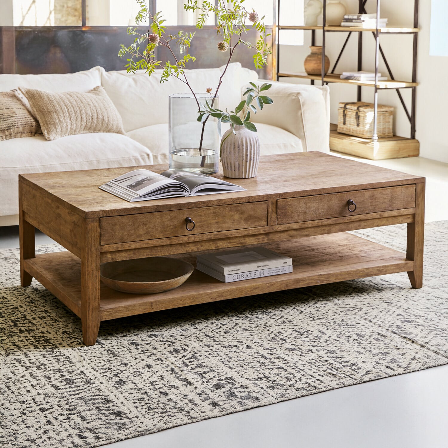 Table basse Rasmus Table basse en bois naturel avec tiroirs et étagère, décorée dans un salon lumineux