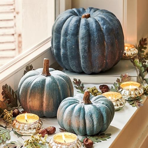 Citrouilles décoratives bleutées sur rebord de fenêtre avec bougies allumées et feuilles d'automne