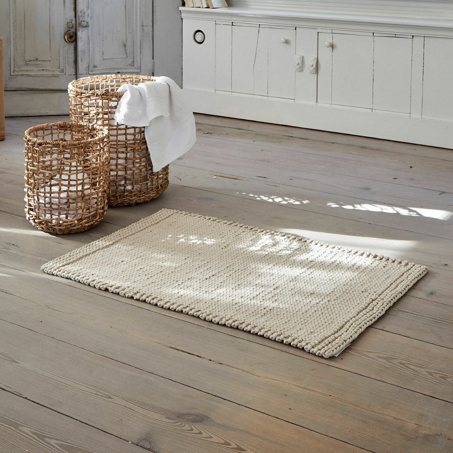 Tapis de bain Carsen Tapis beige en coton sur parquet en bois avec paniers en osier pour rangement