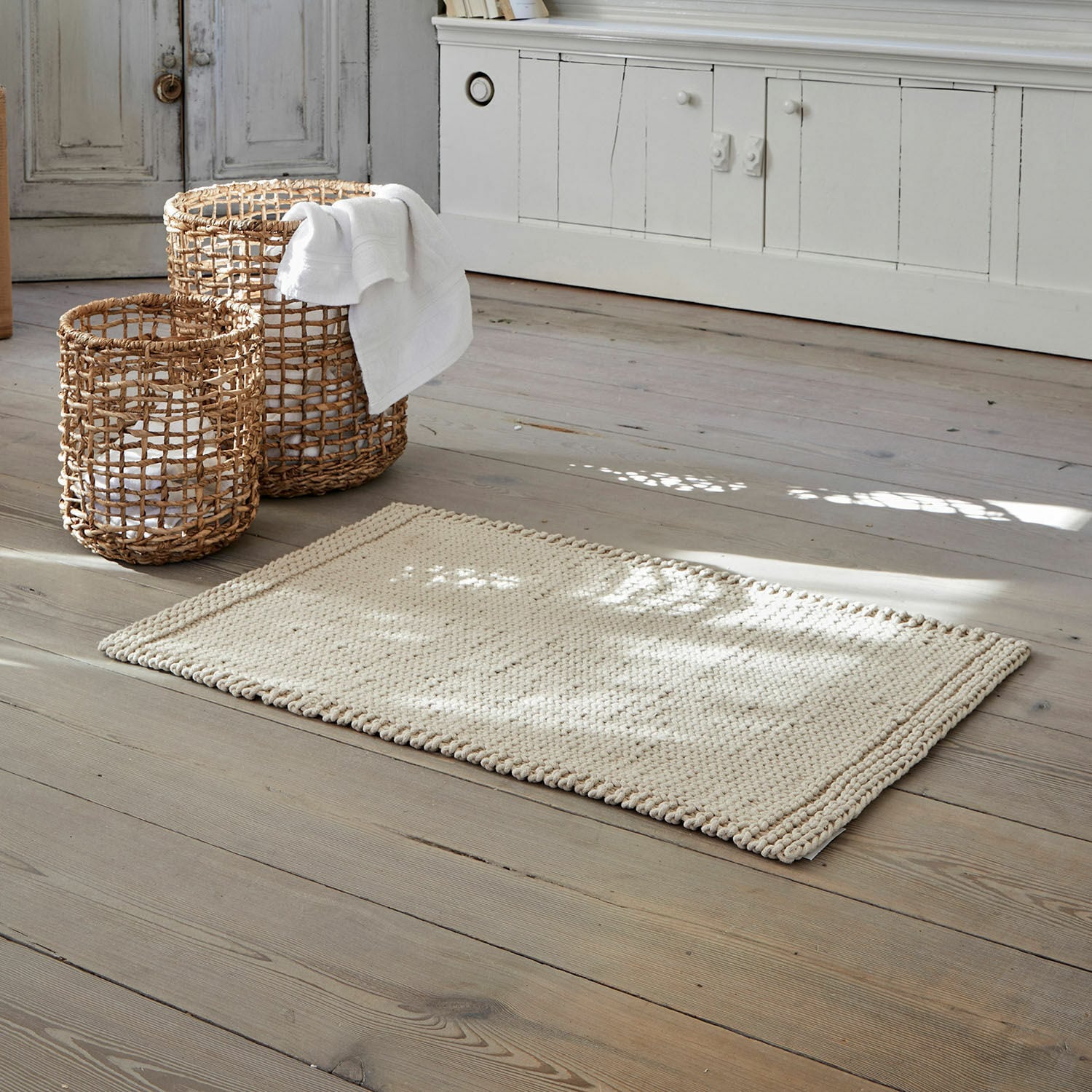 Tapis de bain Carsen Tapis beige en coton sur parquet en bois avec paniers en osier pour rangement