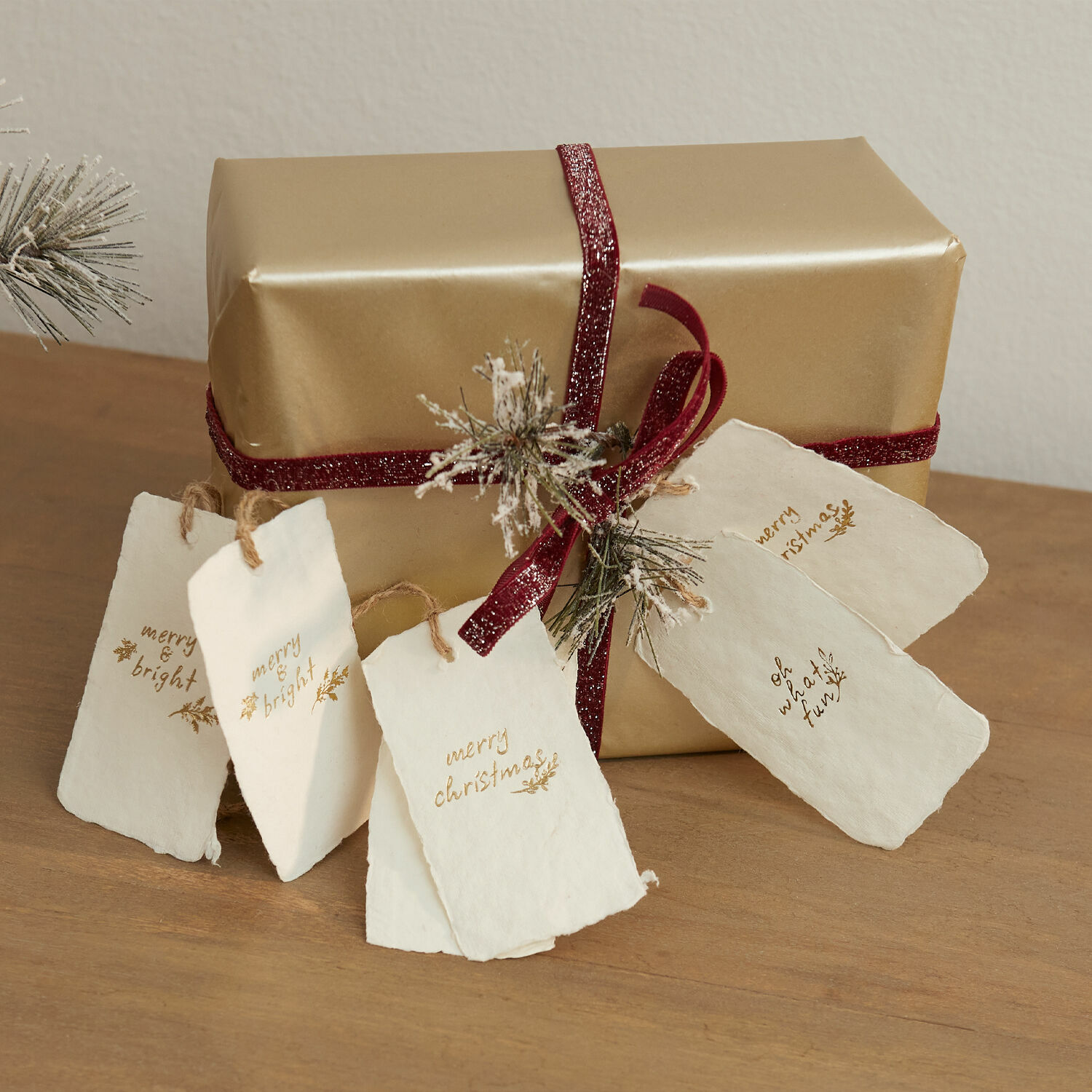 Lot de 6 étiquettes cadeaux Aamira Cadeau doré avec ruban bordeaux et étiquettes en papier blanc de Noël sur table en bois