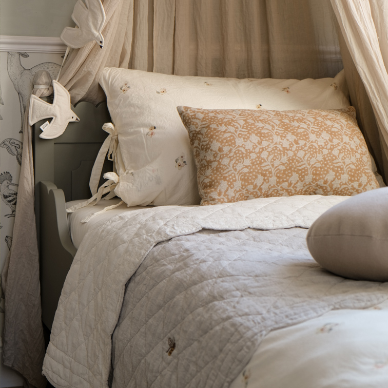 Lit douillet avec coussin beige à motif floral et couette matelassée claire en coton