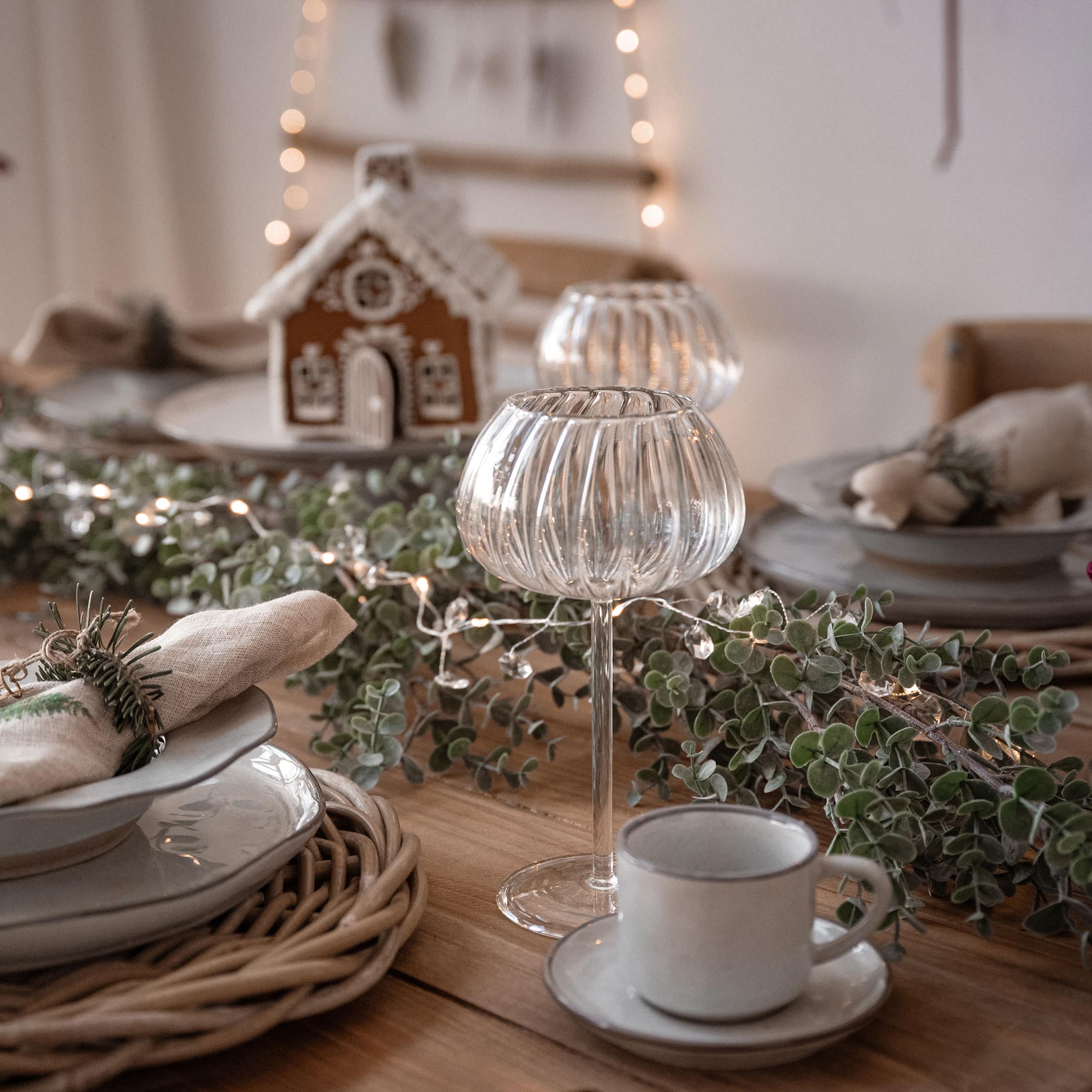 Table de Noël décorée avec des photophores en verre et des branches vertes naturelles