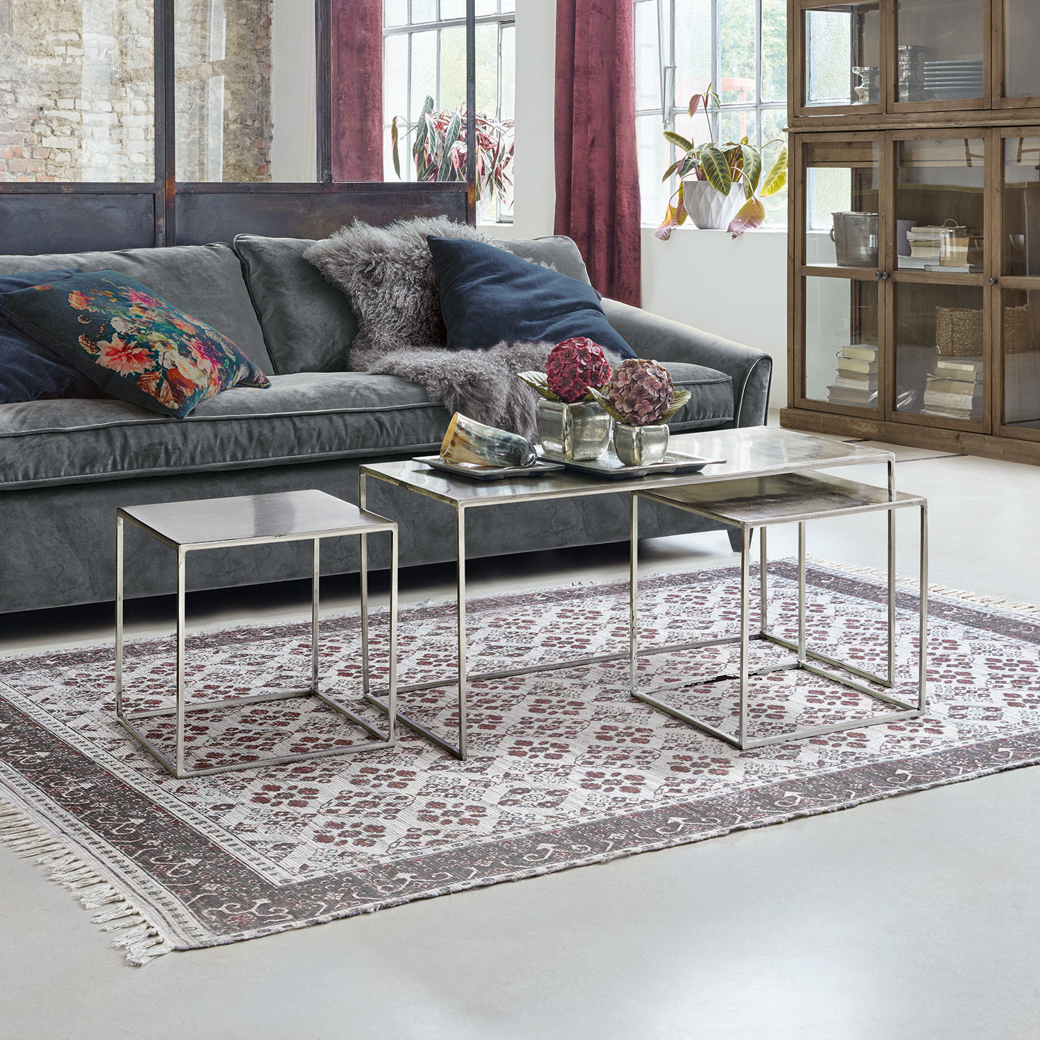 Lot de 3 tables basses Gela Ensemble de trois tables basses avec plateaux en verre et cadres métalliques dans un salon avec canapé gris