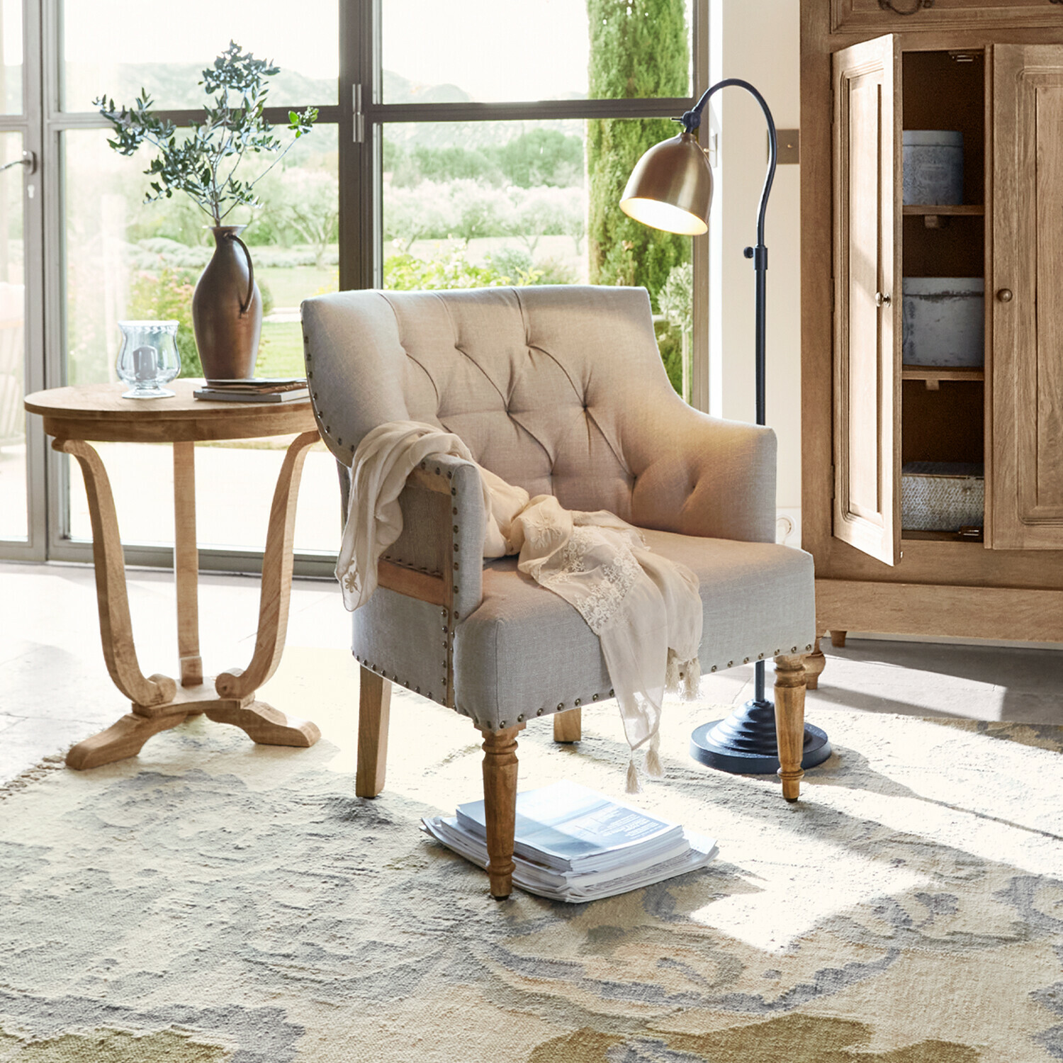 Fauteuil beige en tissu avec pieds en bois dans un salon lumineux avec lampe et table d'appoint