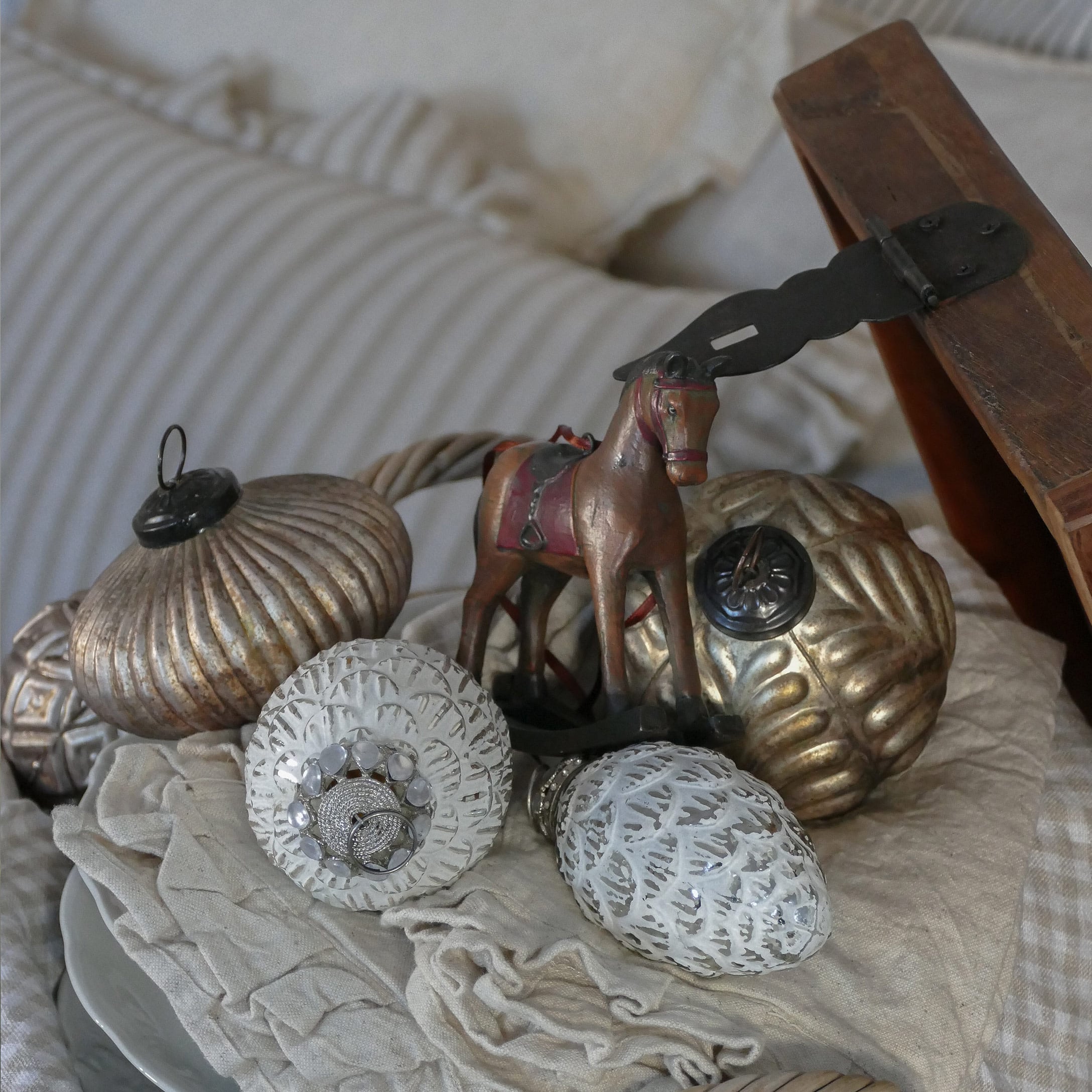 Décorations de Noël dorées et blanches avec une figurine de cheval sur un tissu beige