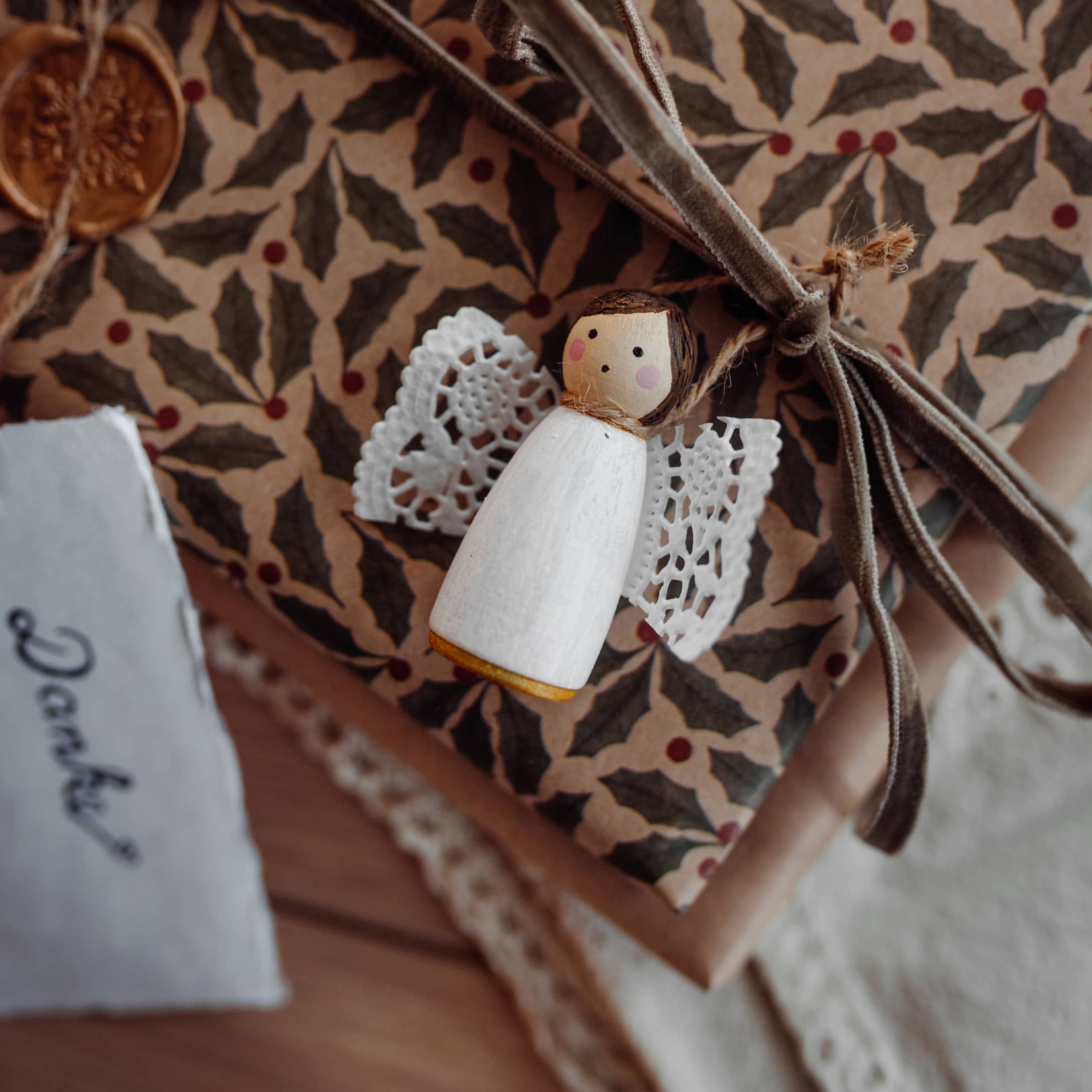 Petit ange en bois blanc avec ailes en dentelle sur des cadeaux emballés dans du papier décoratif