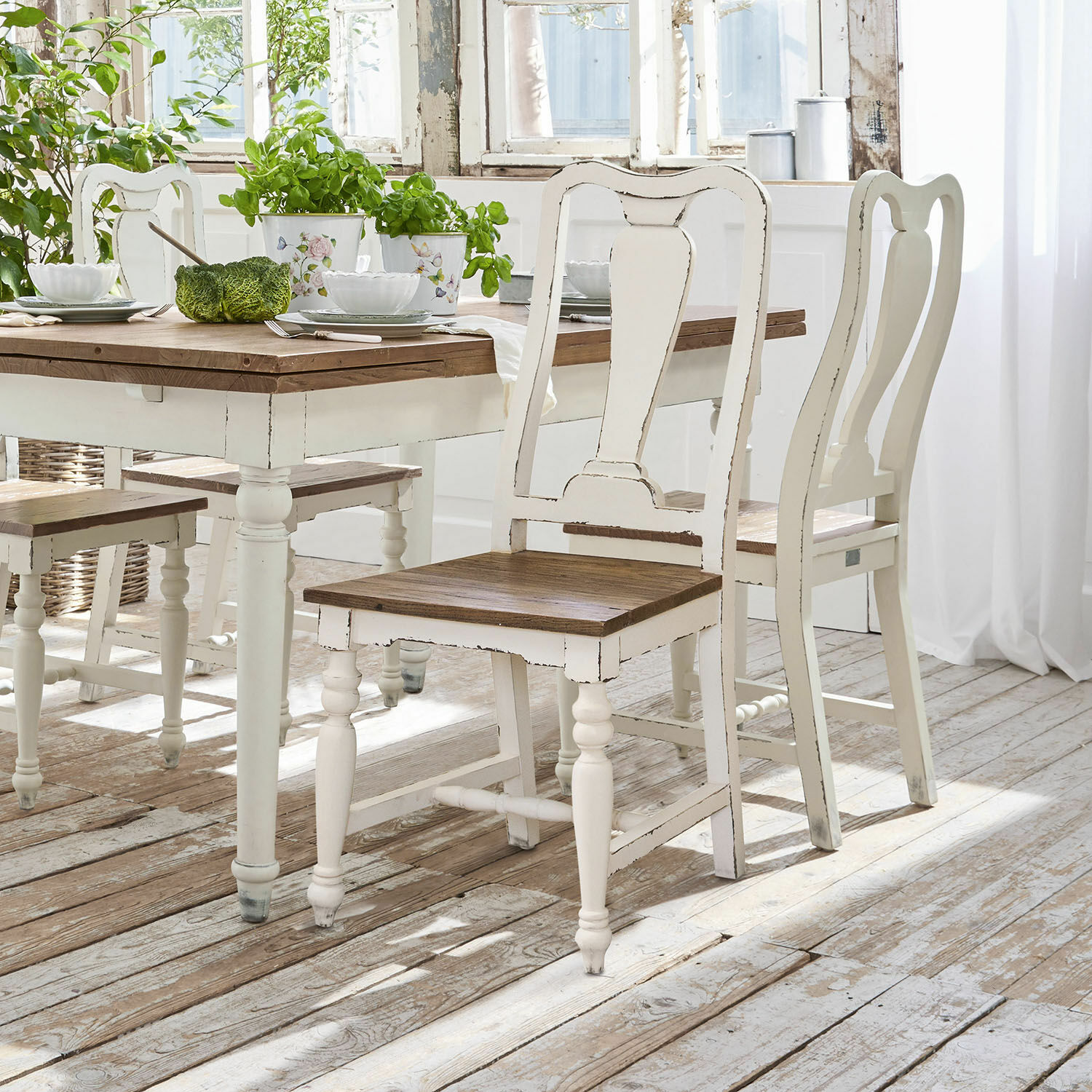 Lot de 2 chaises Harold Chaises et table en bois blanc avec plateau marron dans une salle à manger lumineuse au style rustique