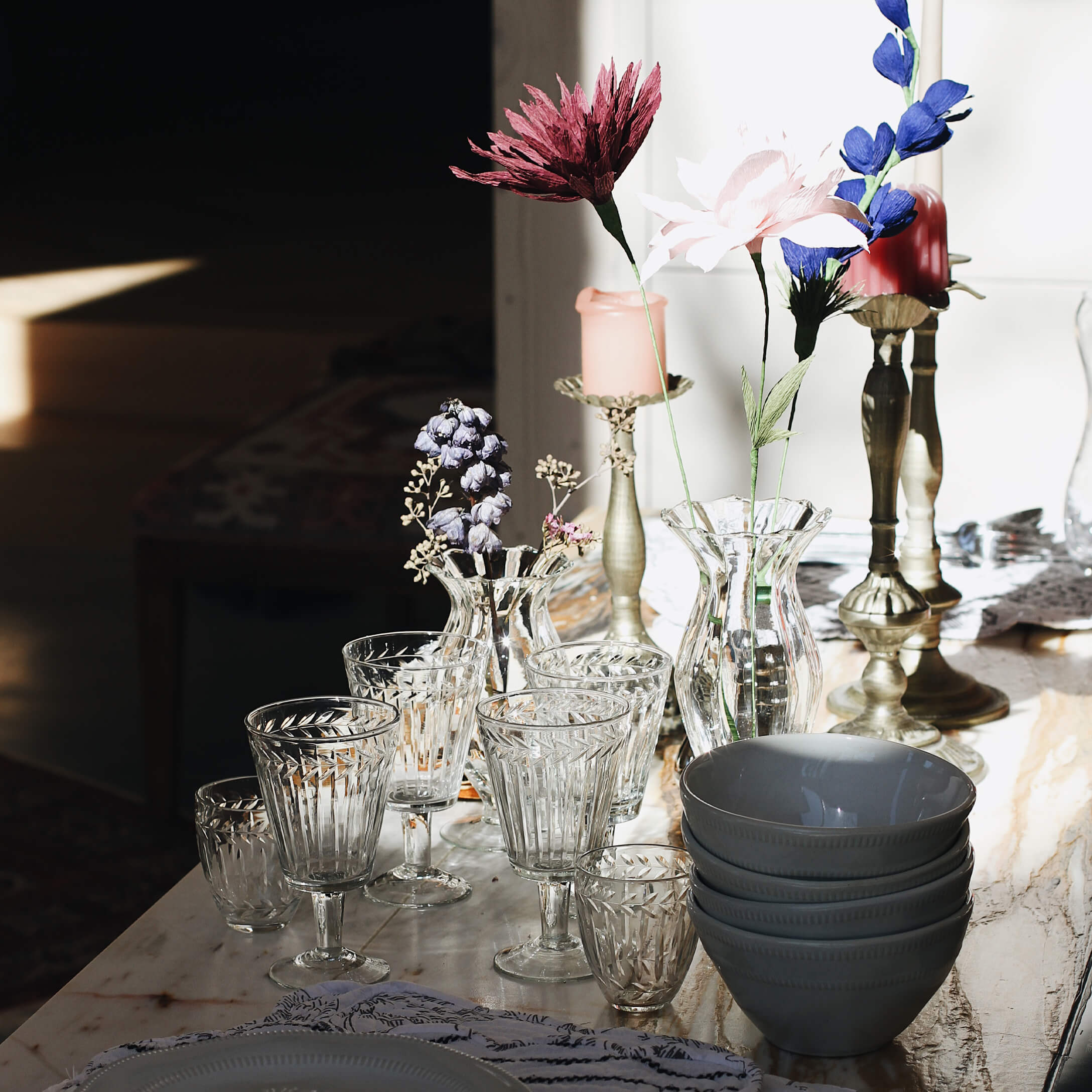 Ensemble de verres et vases en verre transparent avec fleurs et bols en céramique gris sur table en marbre