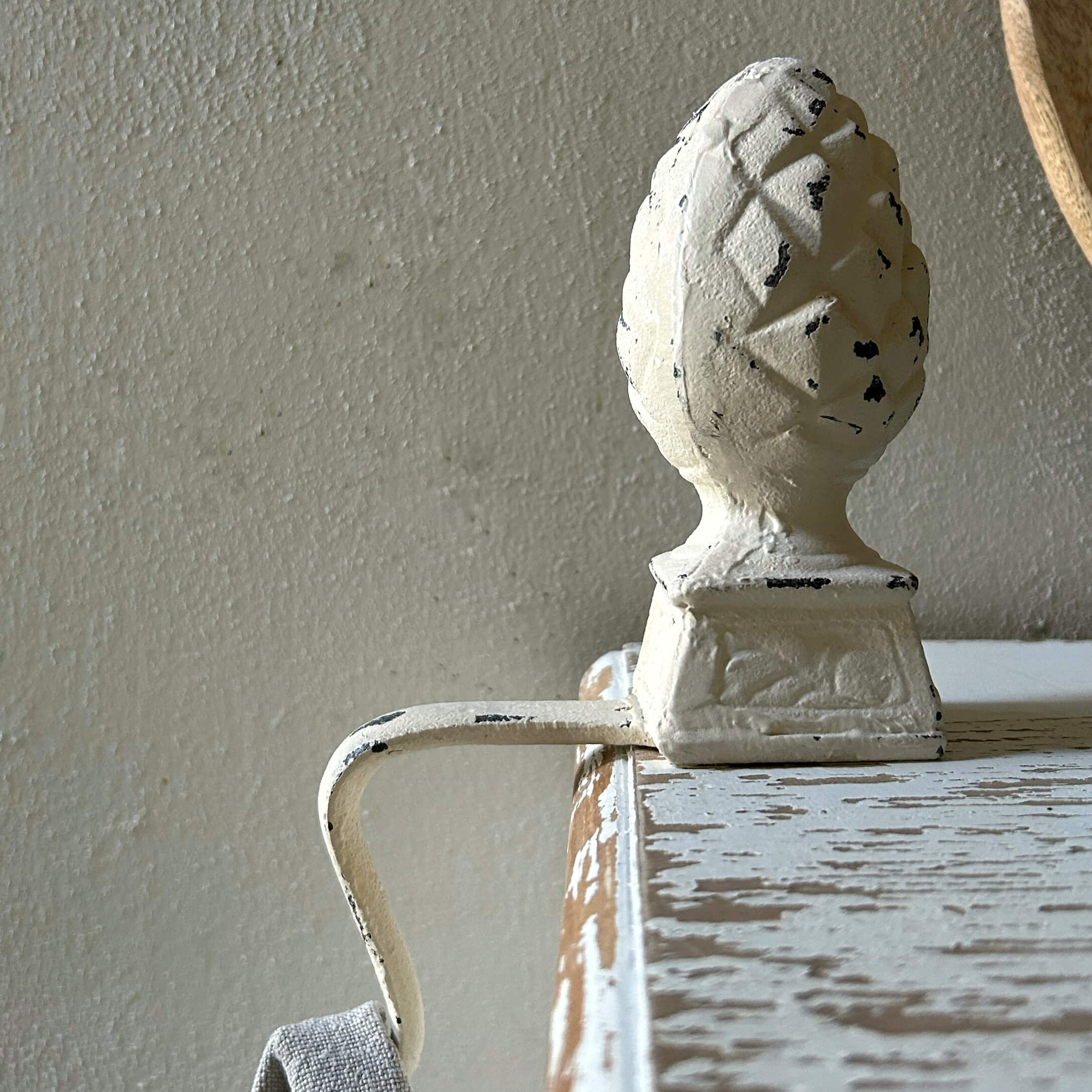 Poignée en métal blanc avec ornement pomme de pin sur meuble en bois vieilli